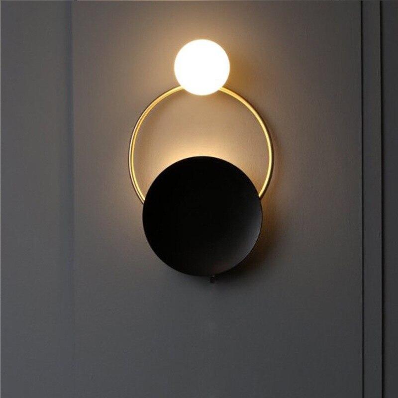 Brushed steel circular wall light with glowing bulb, illuminated ring, and dark disc design.