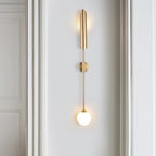 Modern golden wall light with cylindrical top and glowing spherical bulb in sleek vertical design.