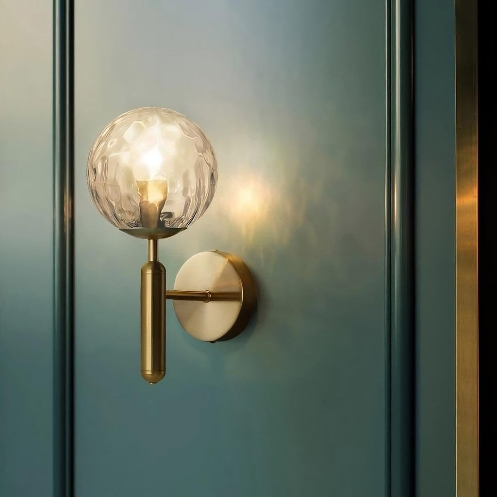 Helena Modern Industrial Glass Wall Light with gold base, round textured glass shade, softly glowing.