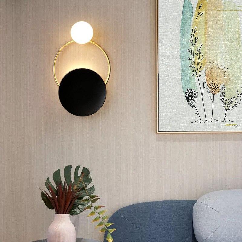 Brushed Steel Circular Glass Wall Light mounted near abstract artwork on a light beige wall.