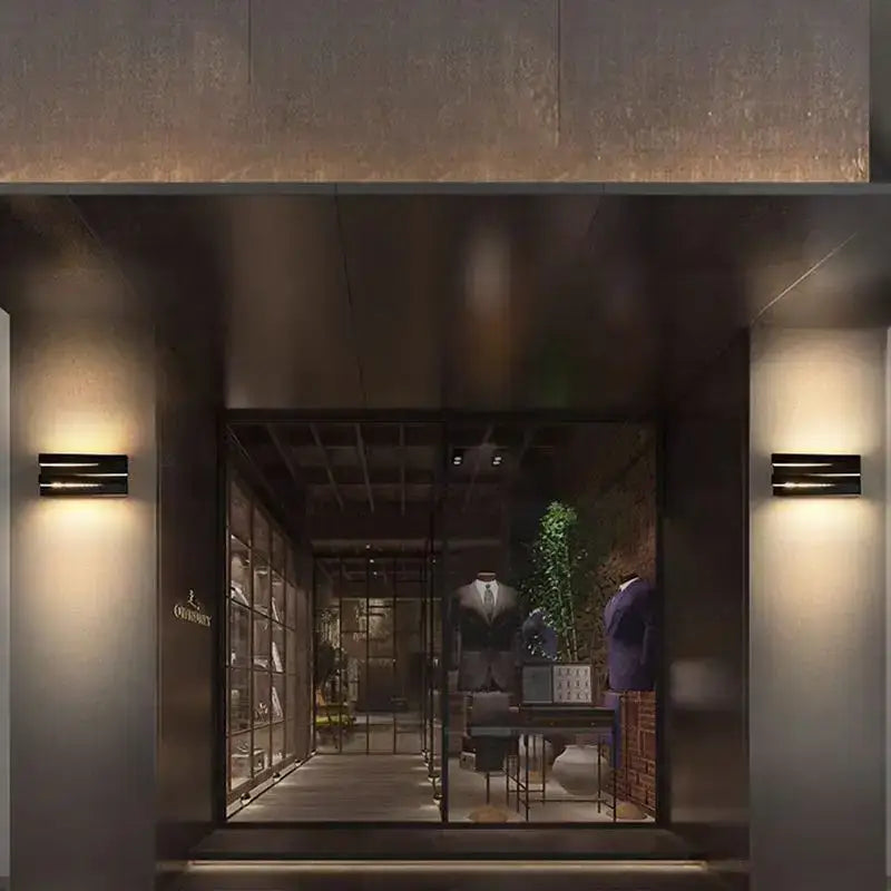 LED Outdoor Wall Light with aluminum frame and borosilicate glass, glowing warmly at night.