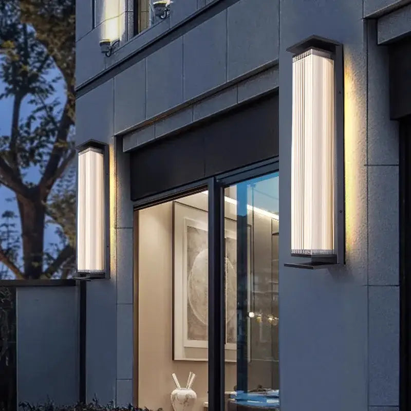Large black outdoor wall light with glass panels, mounted on an exterior building wall.