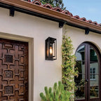Modern black metal outdoor wall light, sleek and geometric, mounted against a stucco wall.