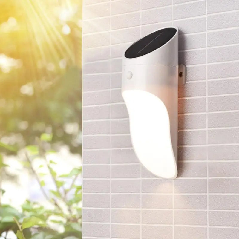 Modern curved Solar Outdoor Wall Light with built-in LED, mounted beneath roof slope on tiles.