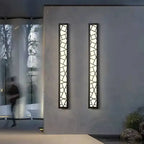 Modern geometric aluminum wall sconce with mosaic pattern mounted on a gray exterior wall.