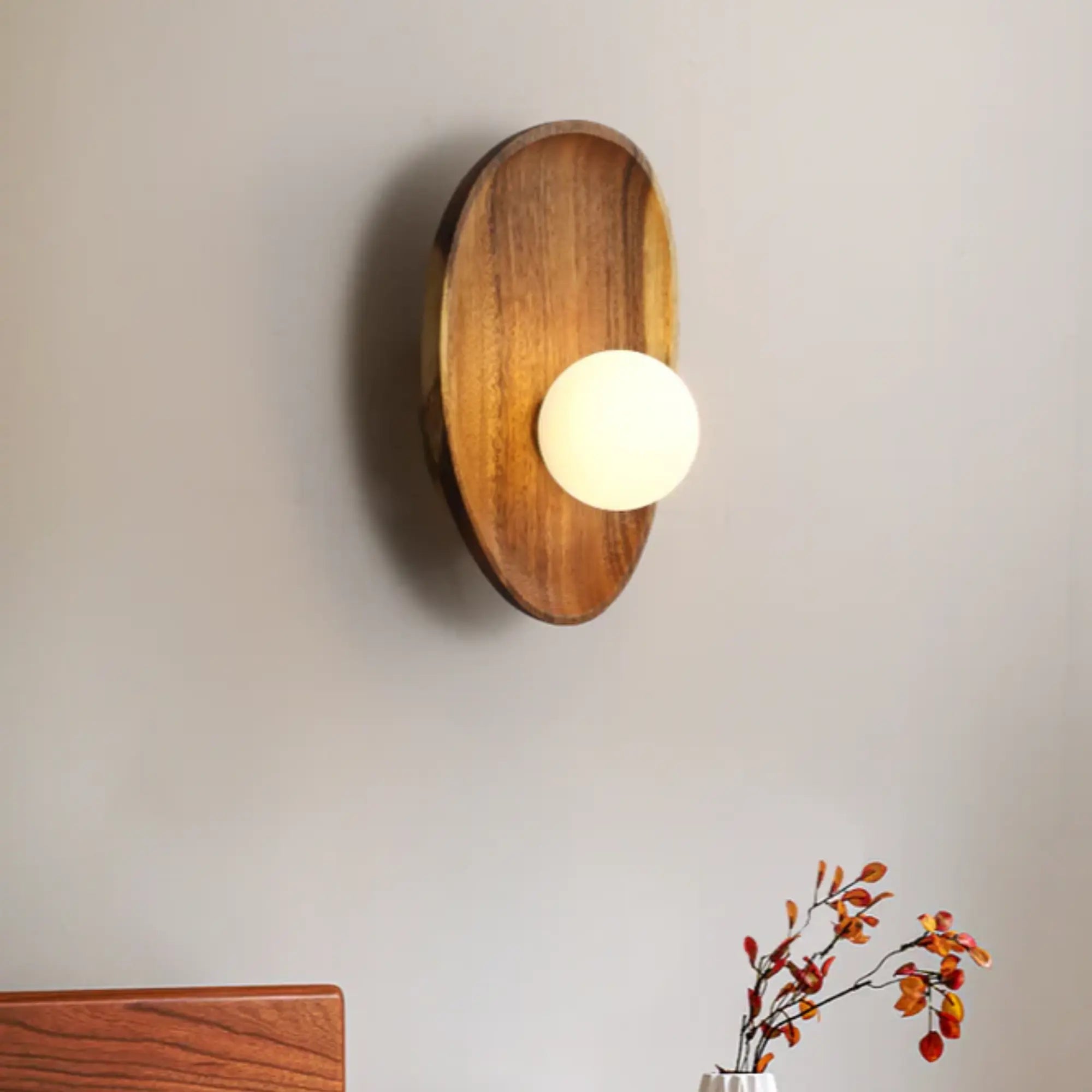 Natural Wood LED Wall Light features a wooden oval backplate and glowing opal diffuser bulb.