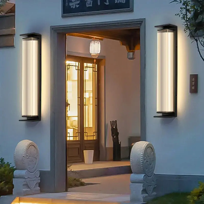 Original Large Black Glass Outdoor Wall Light mounted beside a door, casting warm light at dusk.
