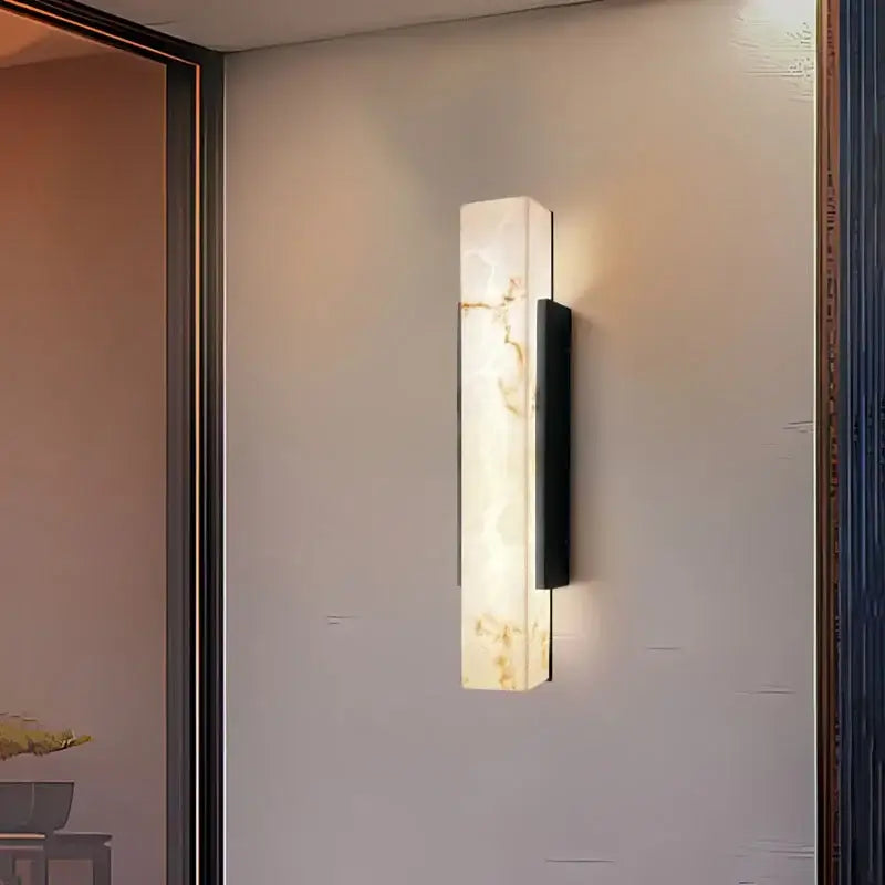Outdoor LED Wall Light with marble effect, emitting a soft warm glow against the wall.