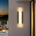 Outdoor LED wall light with marble effect emits a warm, gentle glow on neutral walls.