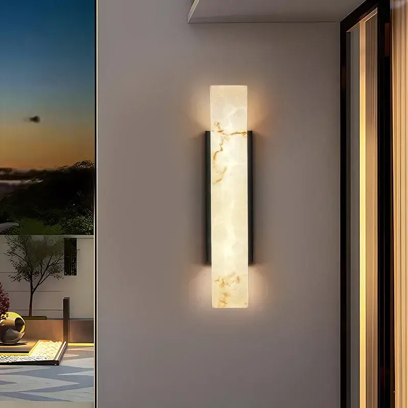 Outdoor LED wall light with marble effect emits a warm, gentle glow on neutral walls.