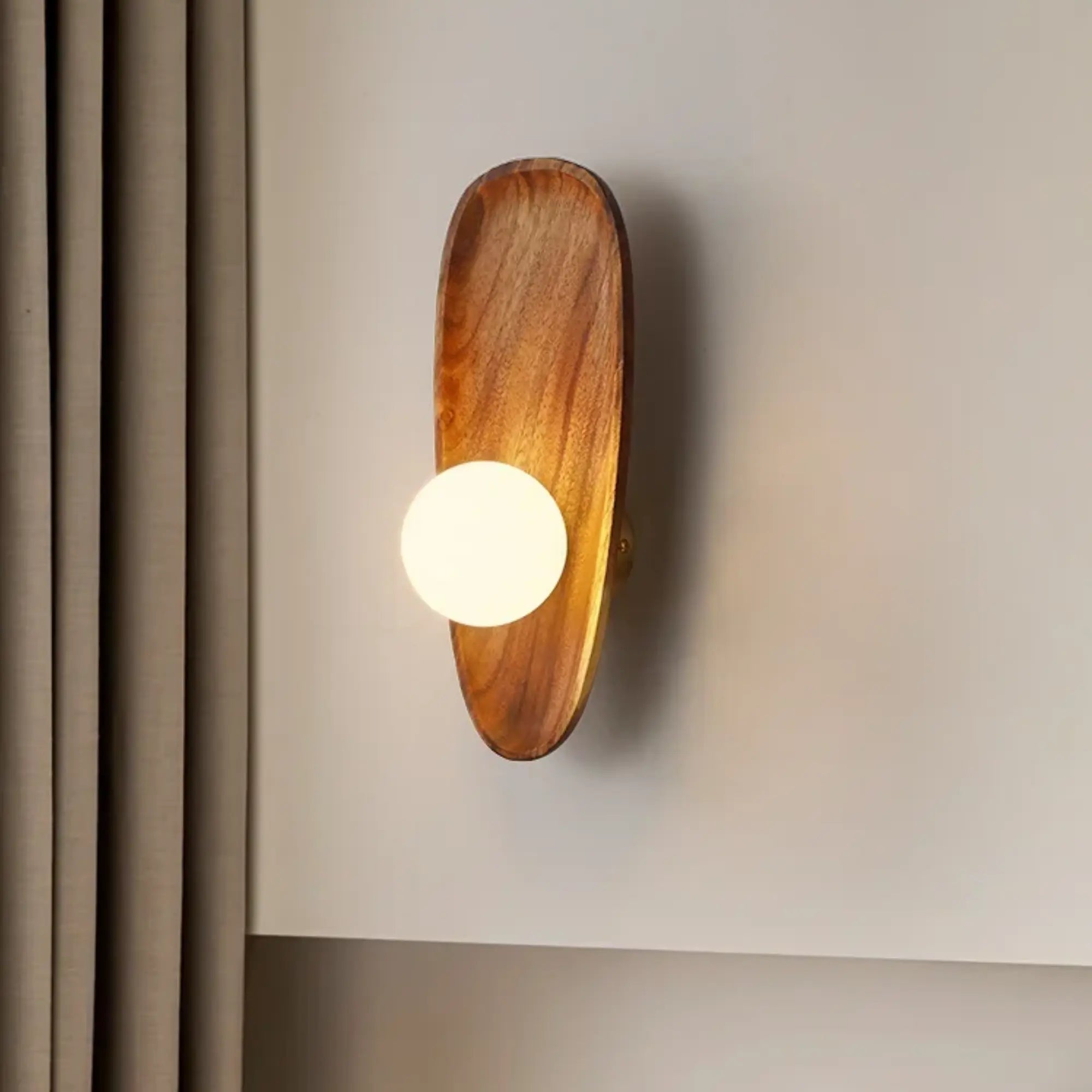 Oval-based natural wood LED wall light with opal diffuser and glowing round bulb.