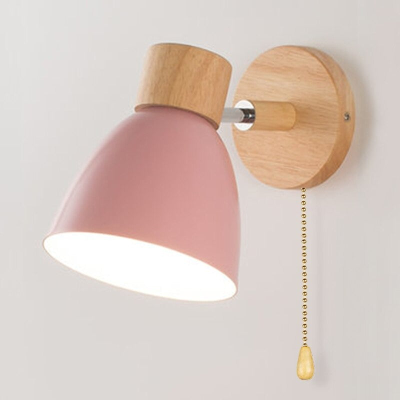 Pink cone-shaped Scandinavian wall light with wood accents and gold pull chain switch.