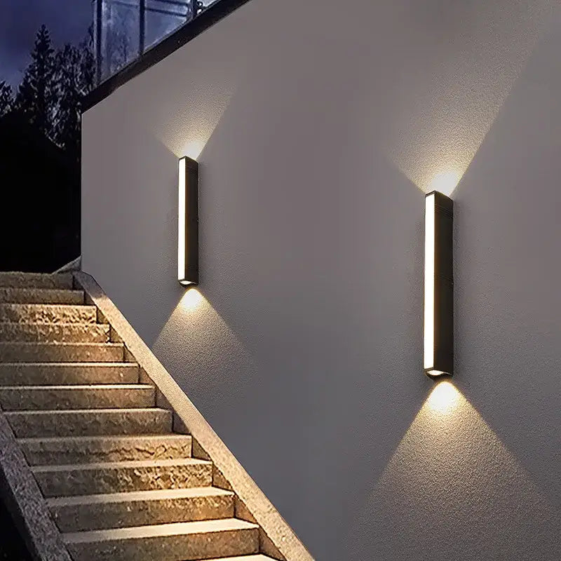 Rectangular aluminum LED wall light emits symmetrical up and down beams on exterior wall.