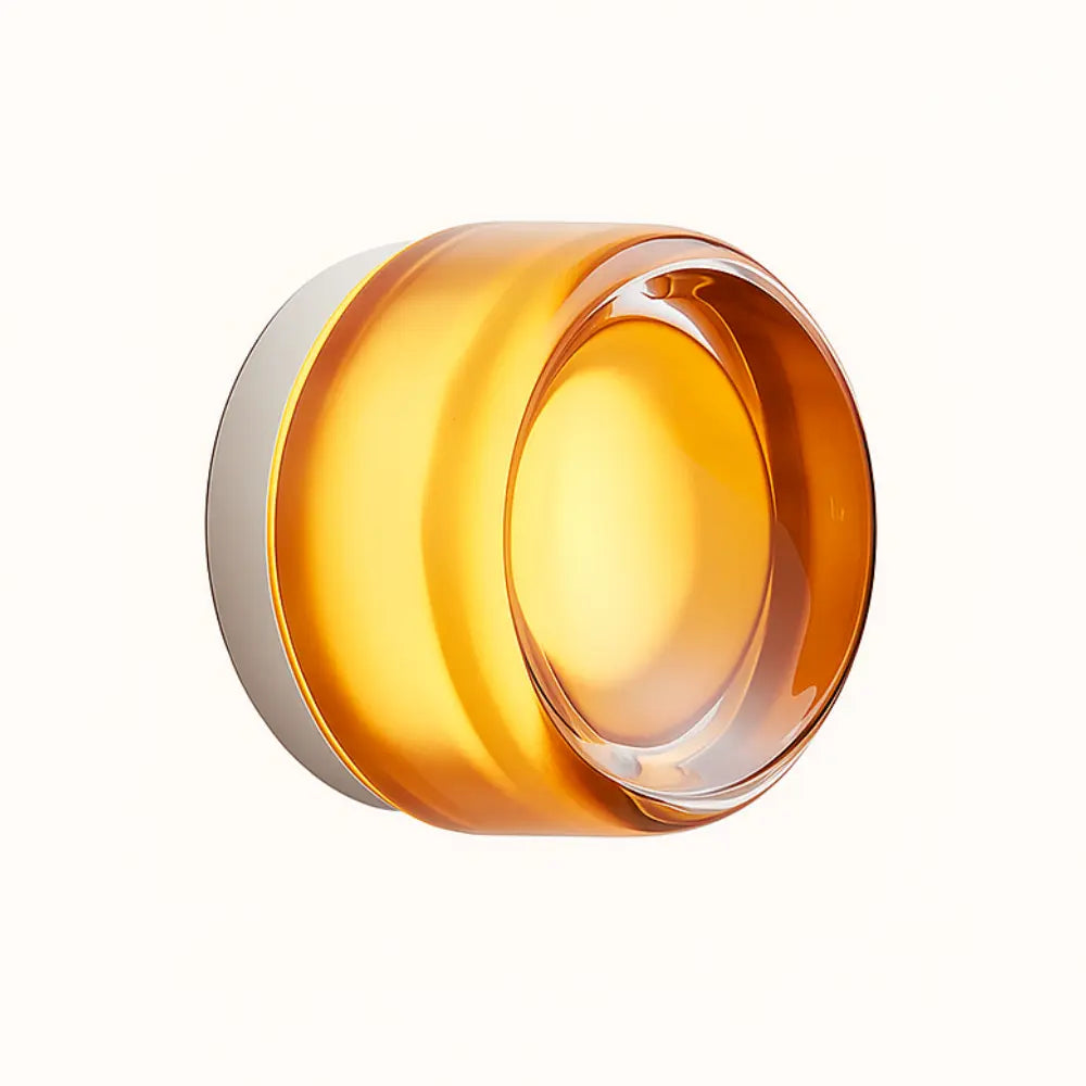 Round amber blown glass wall light with glossy shade on a white circular base.