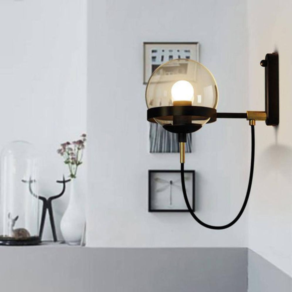 Round glass globe wall light with exposed bulb, black cord, sleek industrial retro style.