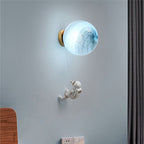 Round glass wall light with glowing shade and tiny astronaut climbing a thin string.