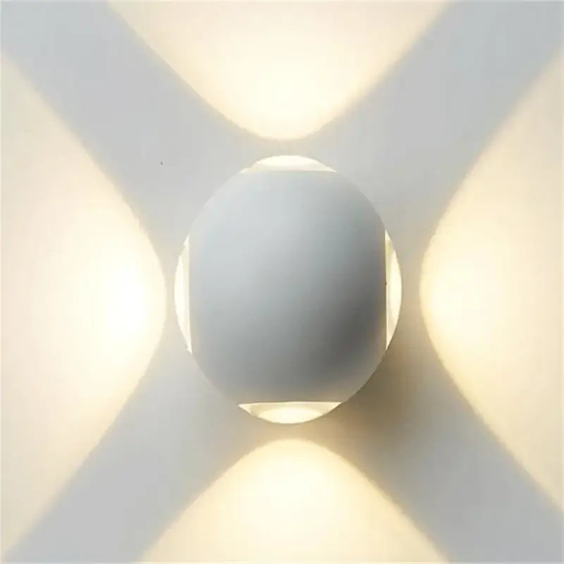 Sleek aluminum and glass LED wall light emits overlapping, soft X-shaped beams on white wall.