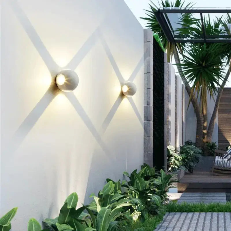 Sleek aluminum and glass wall light emits soft, X-shaped beams; IP65 rated for outdoors.