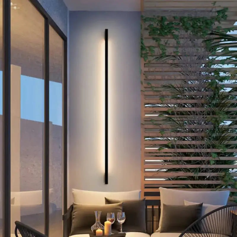 Slim Outdoor LED Wall Light in Aluminum mounted on an exterior wall, glowing softly.