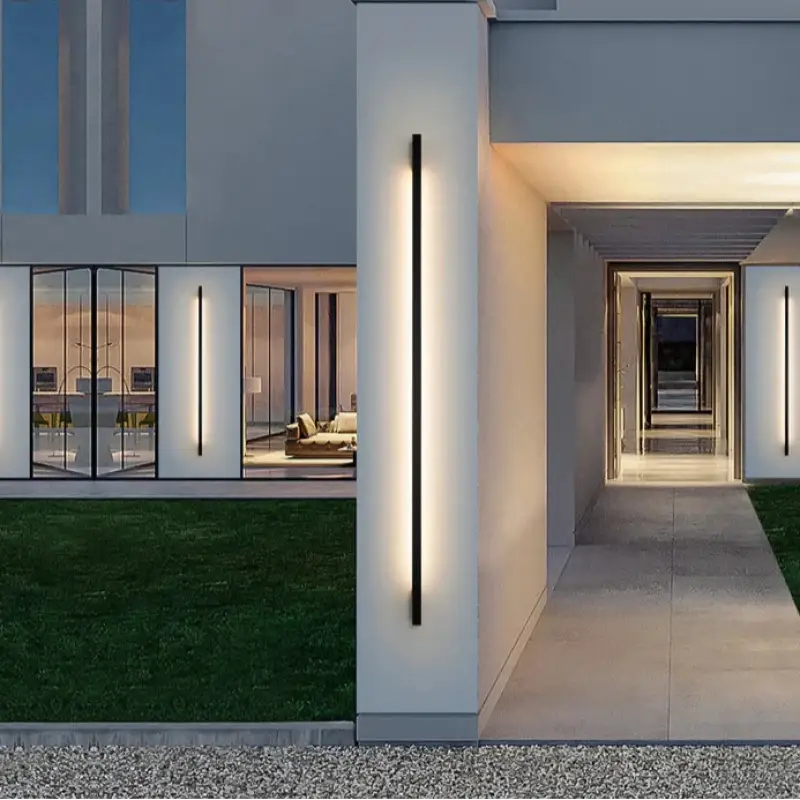 Slim Outdoor LED Wall Lights in Aluminum, casting light along the modern house’s exterior wall.