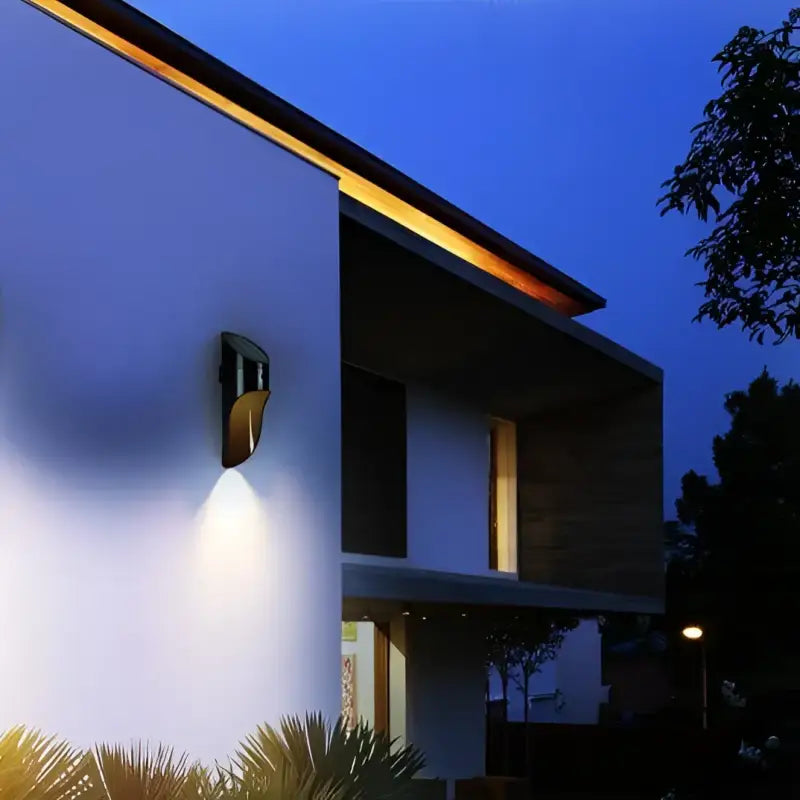 Solar Outdoor Wall Light with integrated LED mounted under roof slope, emitting warm evening glow.