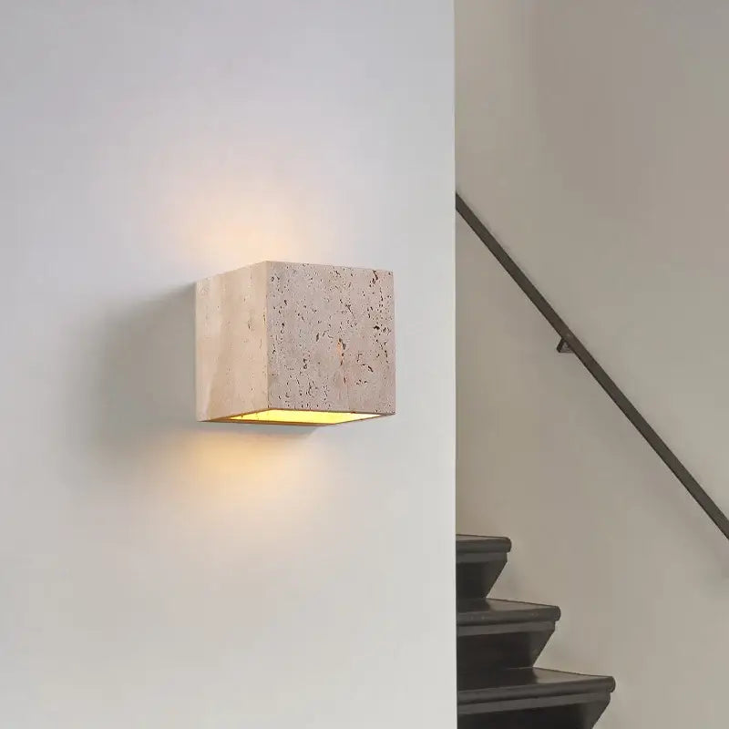 Textured pumice volcanic-style wall sconce with minimalist stone-effect, softly illuminating nearby surfaces.
