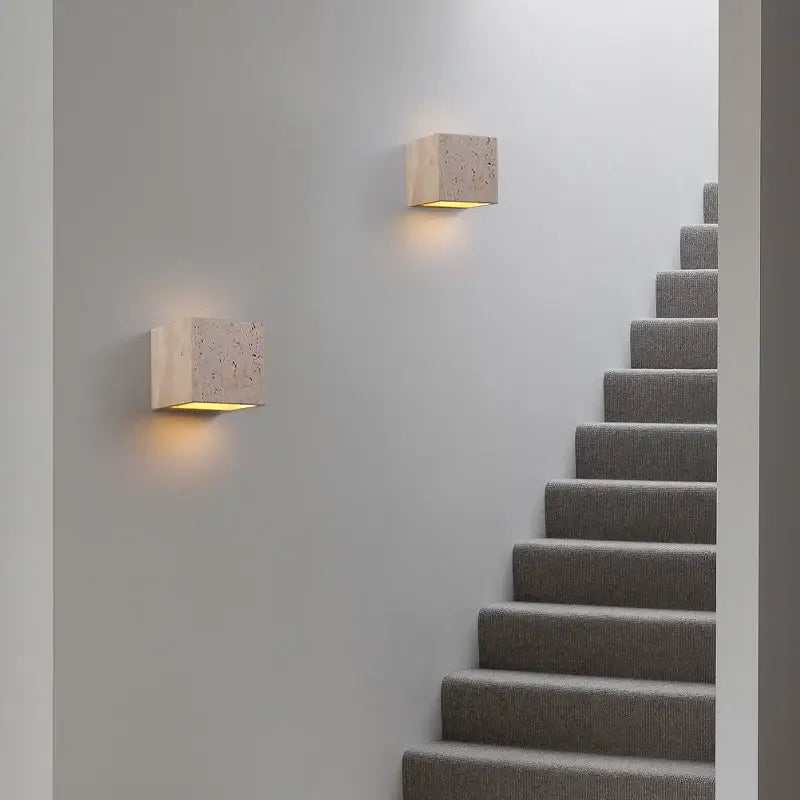 Textured pumice volcanic style wall sconce emits soft, warm light on a plain white wall.