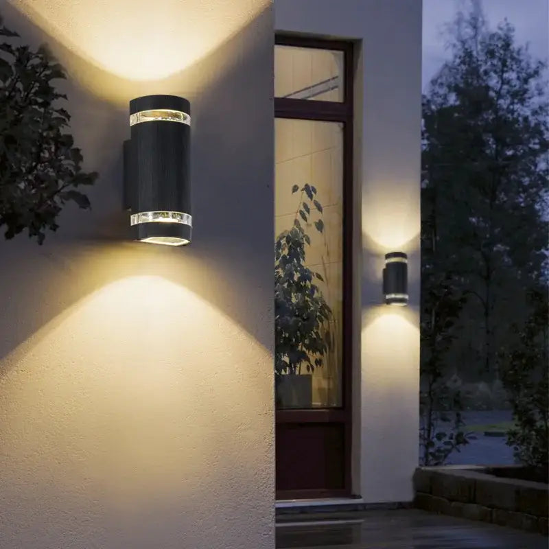 Sleek black cylinder wall light emits warm up and down LED light, IP65 rated.