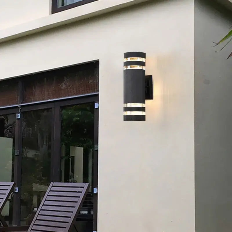 The Classic Cylinder LED-compatible black outdoor wall light with IP65 rating mounted on cream wall.