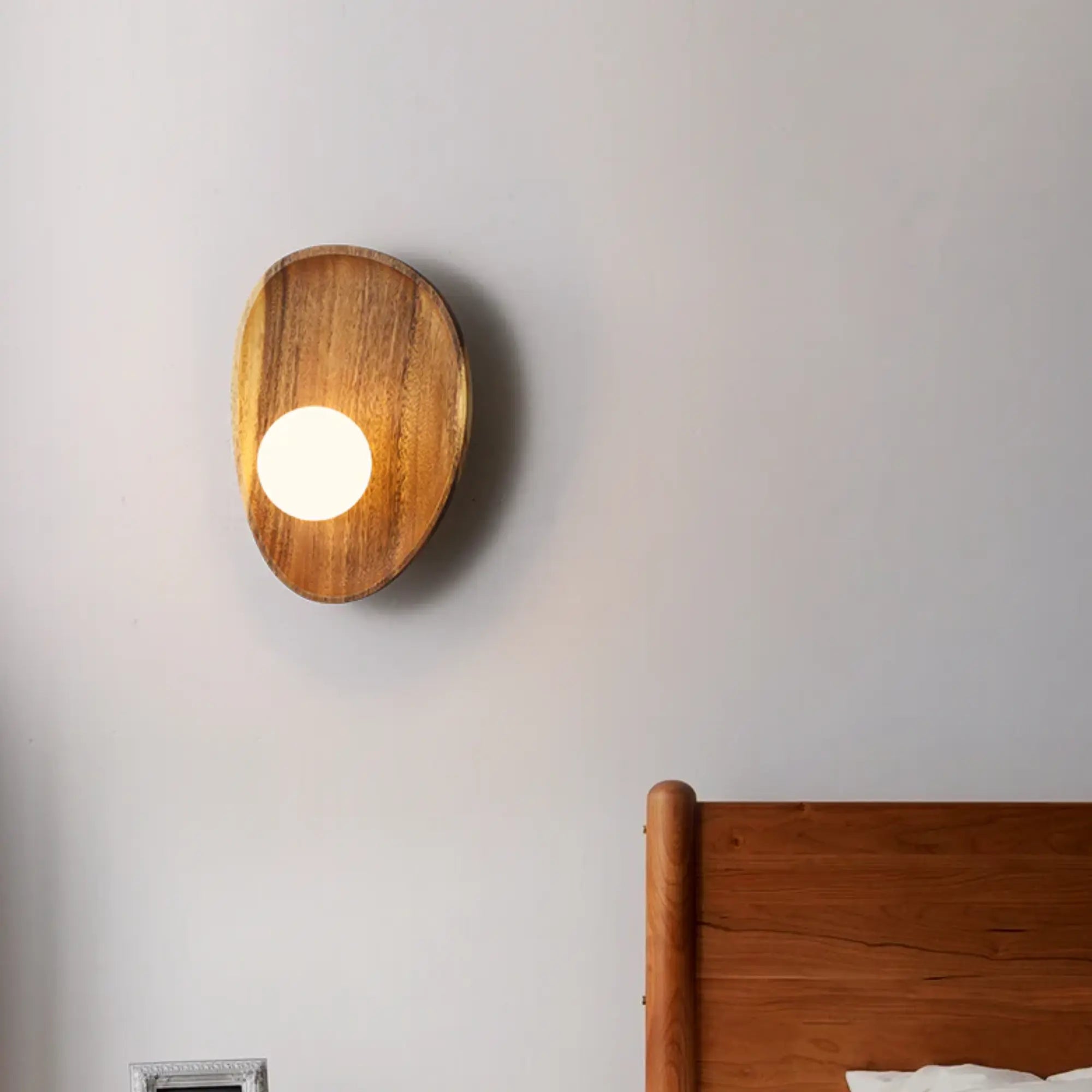 The Natural Wood LED Wall Light with Opal Diffuser emits a warm, soft glow.
