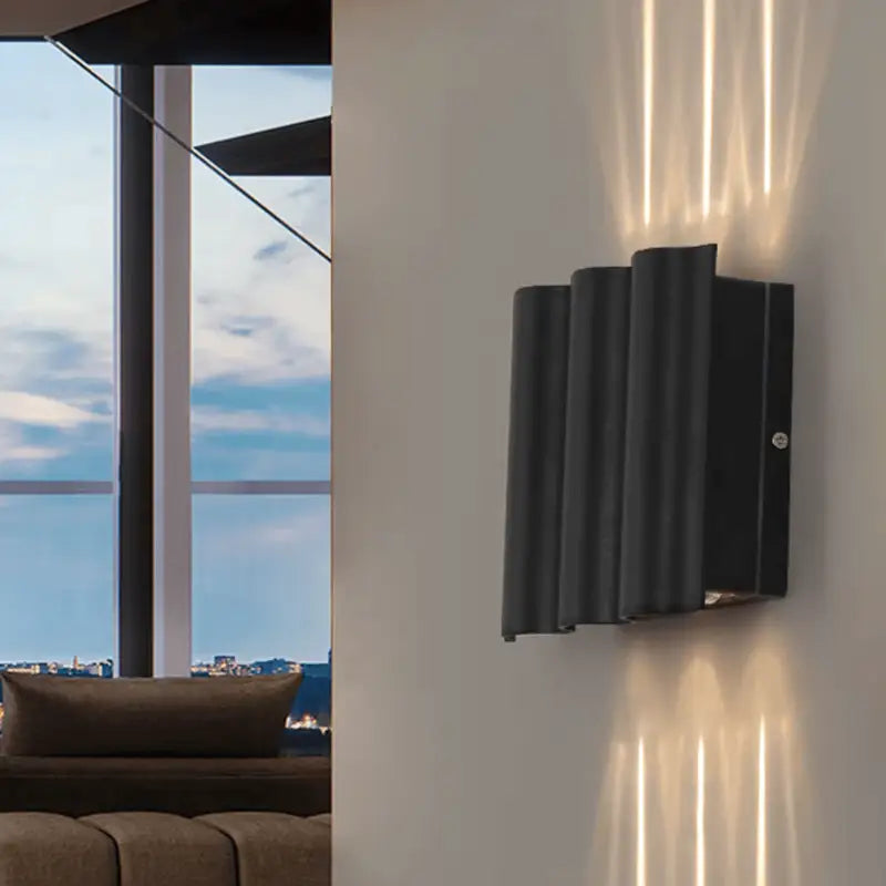The Outdoor LED Curved Design Aluminum Wall Light casts gentle vertical beams on a beige wall.