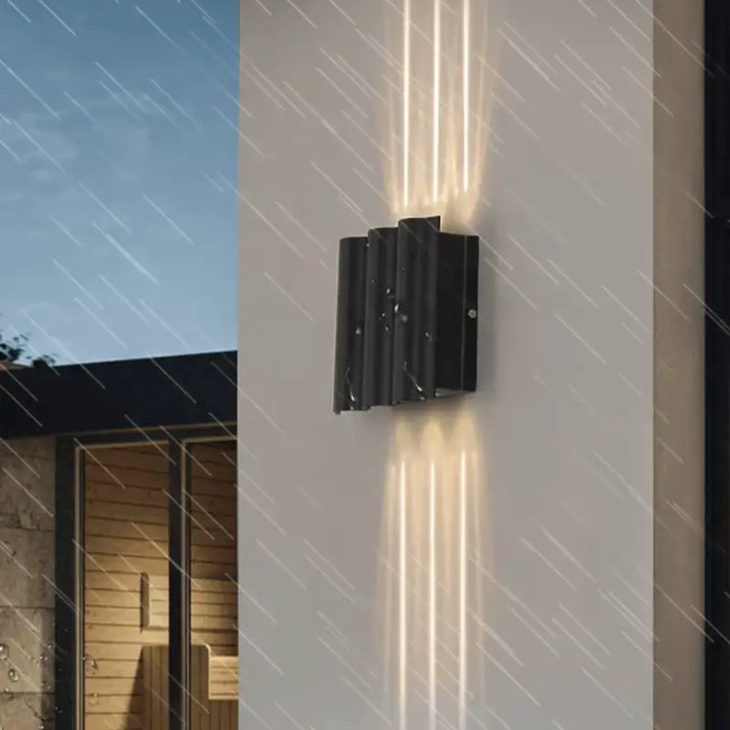 The Outdoor LED Curved Design black wall light casts up and down beams in rain.
