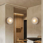 Two circular glass wall lights emit a warm glow against modern beige walls.