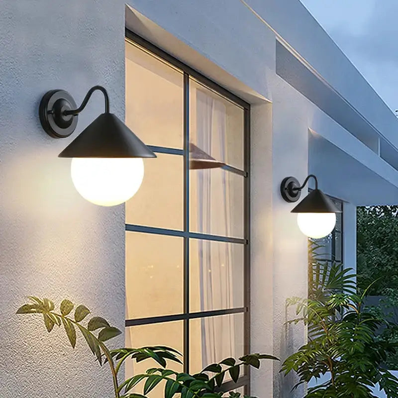 Two modern black outdoor wall lights with white glass and round bulbs, illuminated at night.