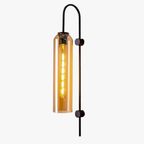 Vertical black metal rod with a cylindrical amber glass shade and visible glowing filament bulb.