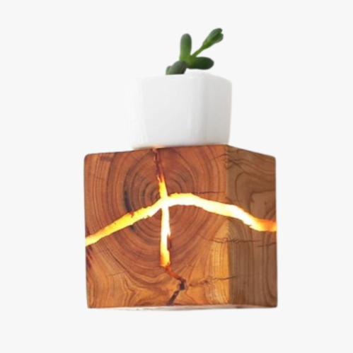 Wooden cube LED wall light with glowing cracks and visible tree rings, radiating warm charm.