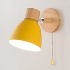 Yellow-shaded wall light with wooden base and pull chain, adjustable rotation, warm downward glow.