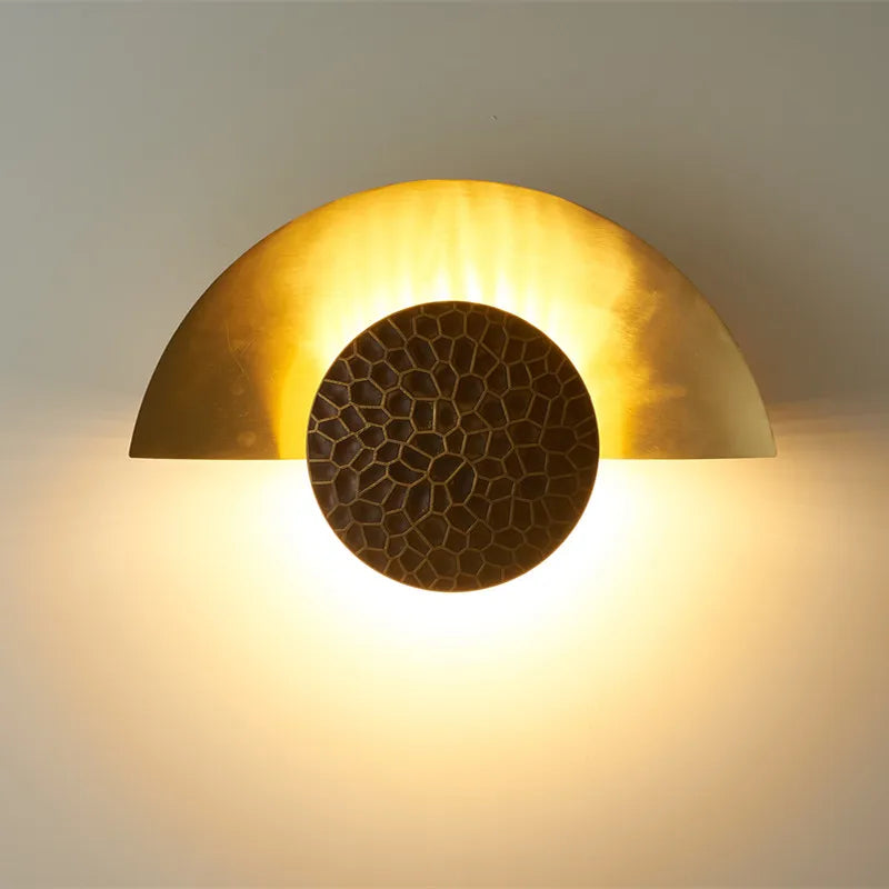 Luminaire demi-lune doré Art Déco, laiton texturé, centre sombre effet soleil.