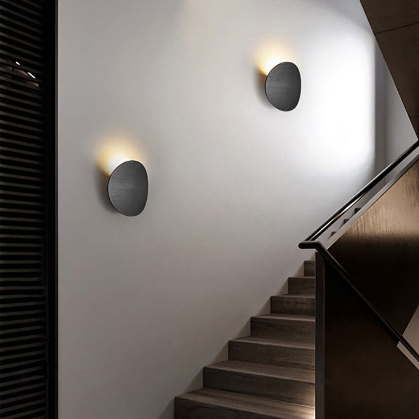 Soft, circular LED wall lights cast a gentle upward glow on the white wall.
