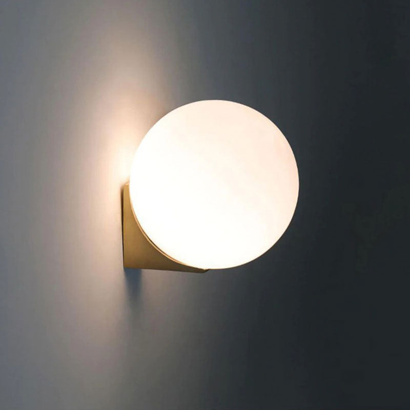Elegant accent lighting with a round frosted glass shade and gold base brightens walls.