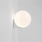 Minimalist wall light with a glowing white spherical glass shade illuminates modern spaces.