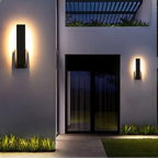 Le luminaire mural extérieur noir diffuse une lumière chaude dans un design moderne élégant.