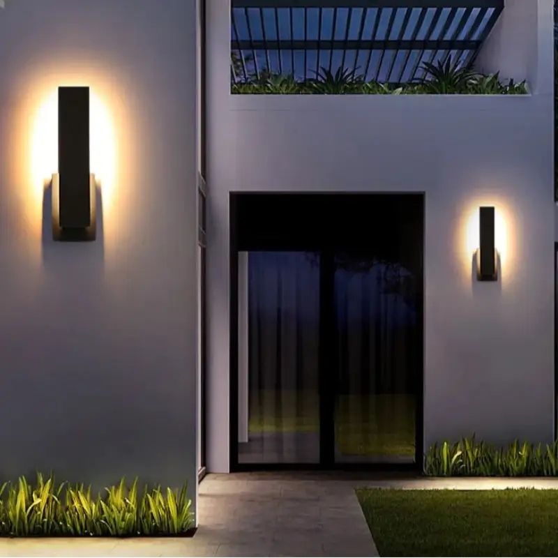 Le luminaire mural extérieur noir diffuse une lumière chaude dans un design moderne élégant.