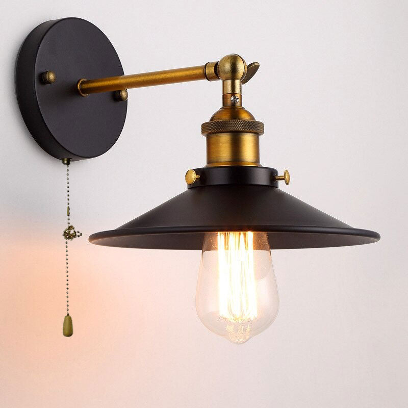 Vintage wall light with metal shade, brass details, and glowing exposed bulb for ambiance.