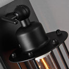 Industrial black iron wall light with exposed screws casts warm glow through clear bulb cover.