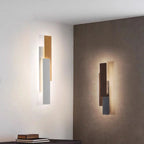 Rectangular wooden LED wall lights with overlapping panels cast a warm, dimmable glow.