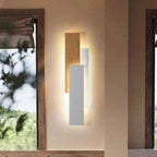 Soft, dimmable warm light glows from overlapping wood and white panels on the wall.