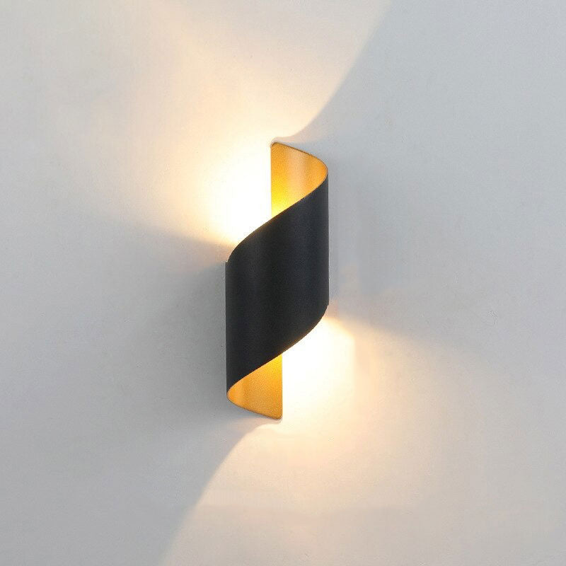 Warm yellow light glows up and down from a twisted black spiral LED wall sconce.