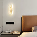 A soft, circular LED wall light creates a cozy, minimalist glow on the white wall.