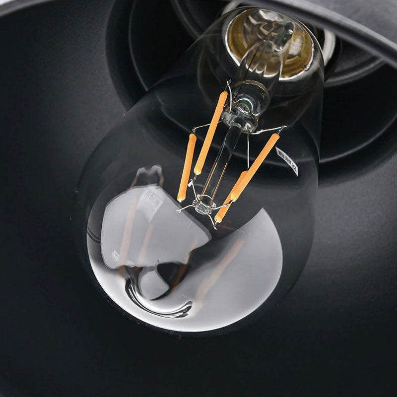 Detailed LED filaments glow inside retro industrial wall light, reflections amplifying illumination.